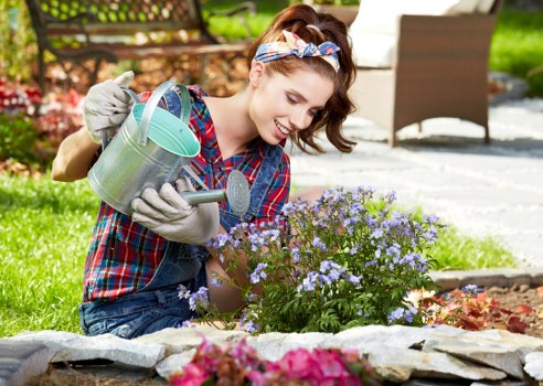 Gardener in protective gear inspecting a landscaped courtyard